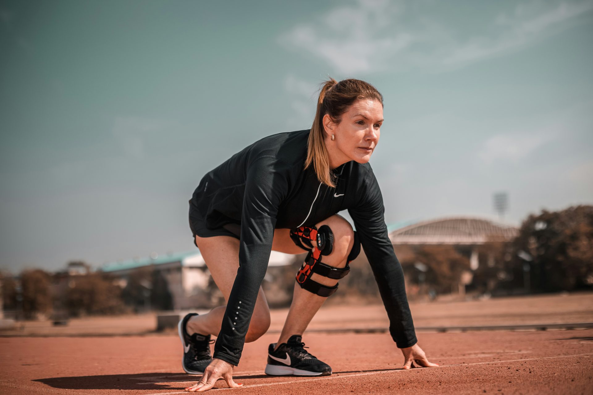 a woman crouches down to pick up a tennis ball